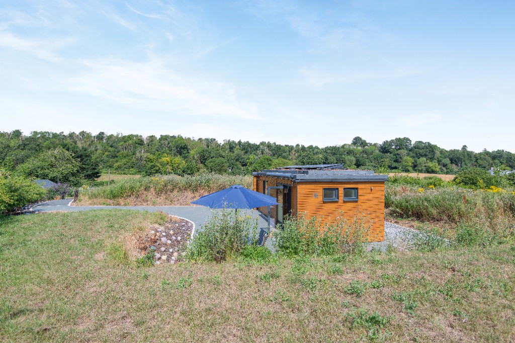 Enchanted Lodge among wildflower meadows with wooden cladding and patio umbrella, Kent countryside